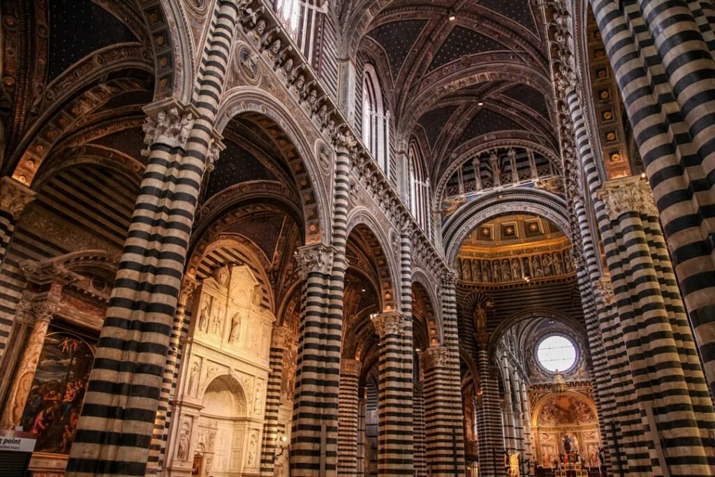 Weitblick über schwarz-weiße Säulen und Arkaden im Duomo von Siena