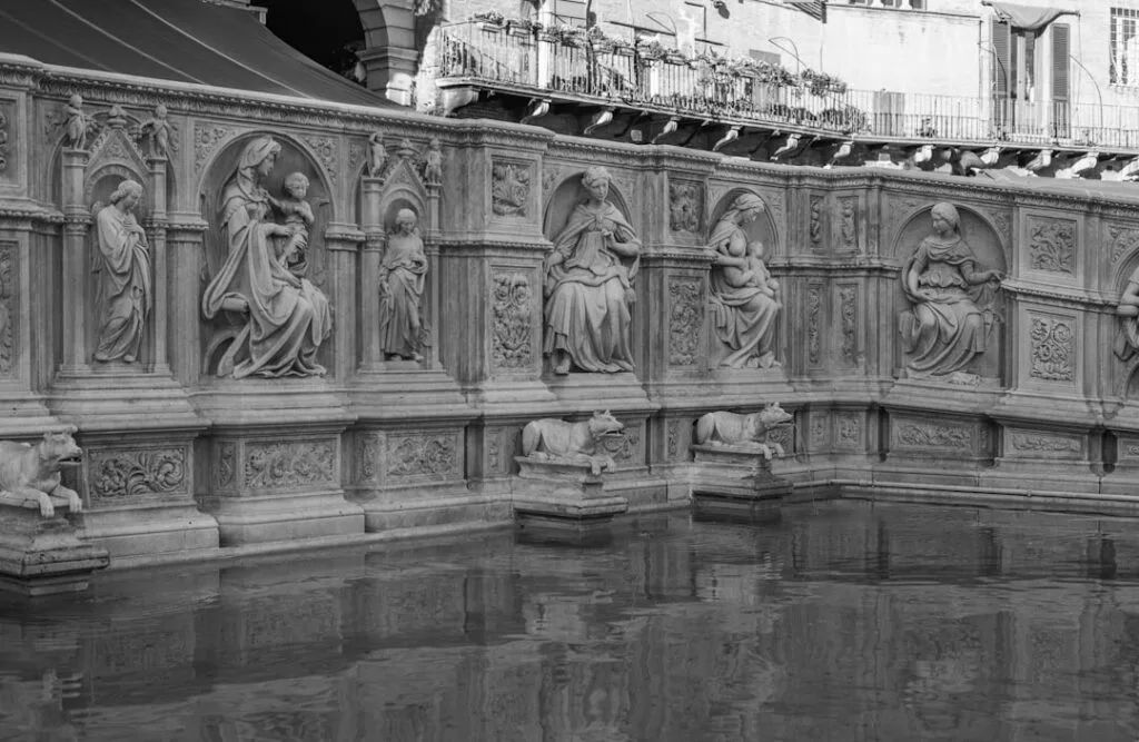 Détails sculptés de la Fonte Gaia à Sienne, reflet dans l'eau