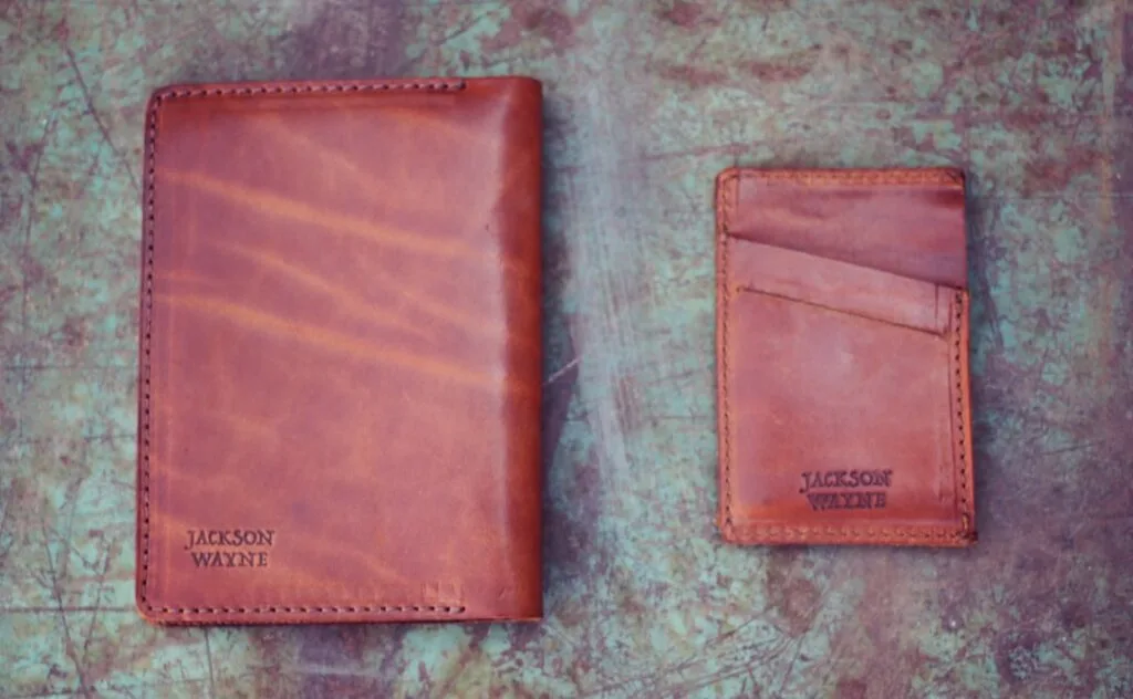 Deux portefeuilles en cuir marron marqués 'Jackson Wayne' sur table
