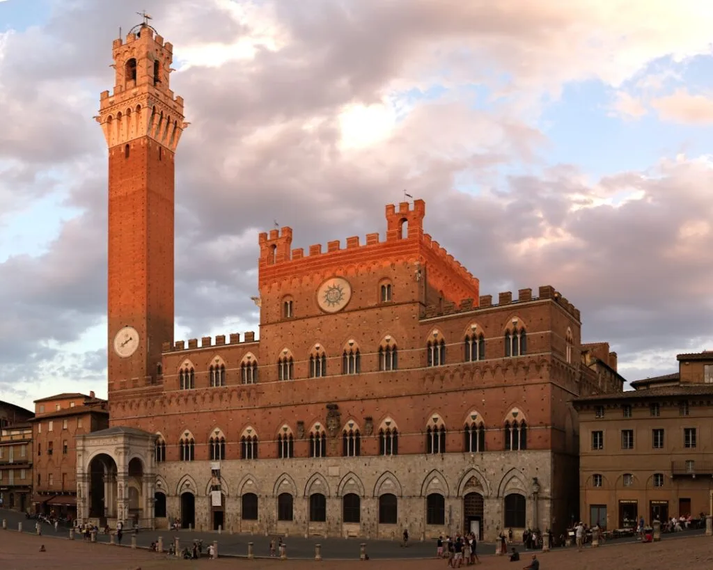 Palazzo Pubblico met Torre del Mangia bij zonsondergang op Piazza del Campo, Siena
