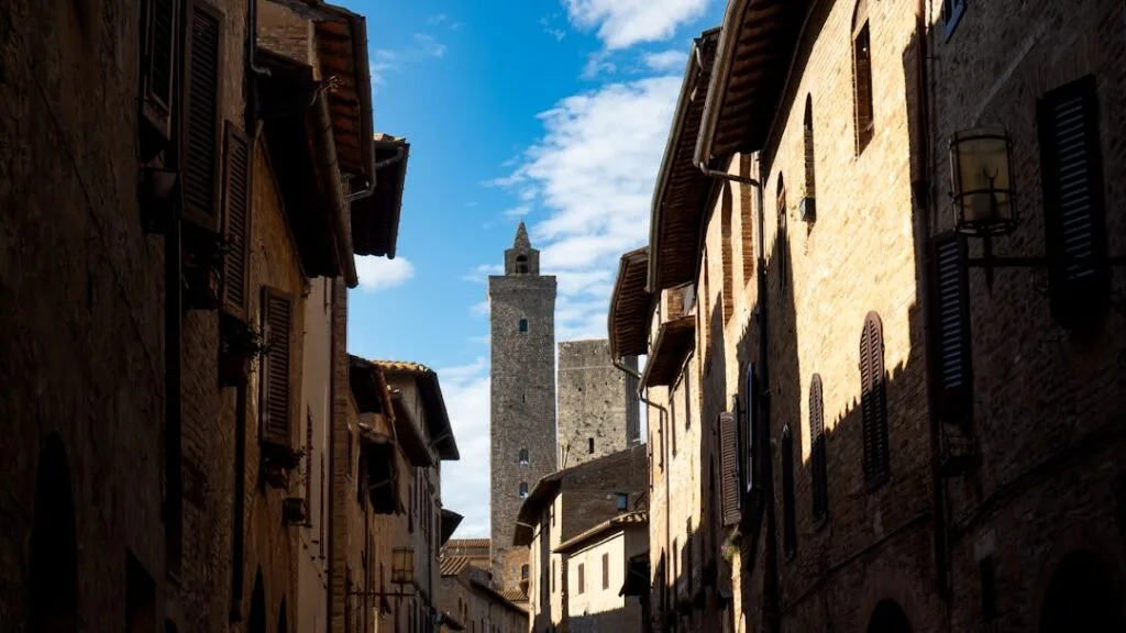 Ruelle ombragée de San Gimignano encadrée par maisons et tour