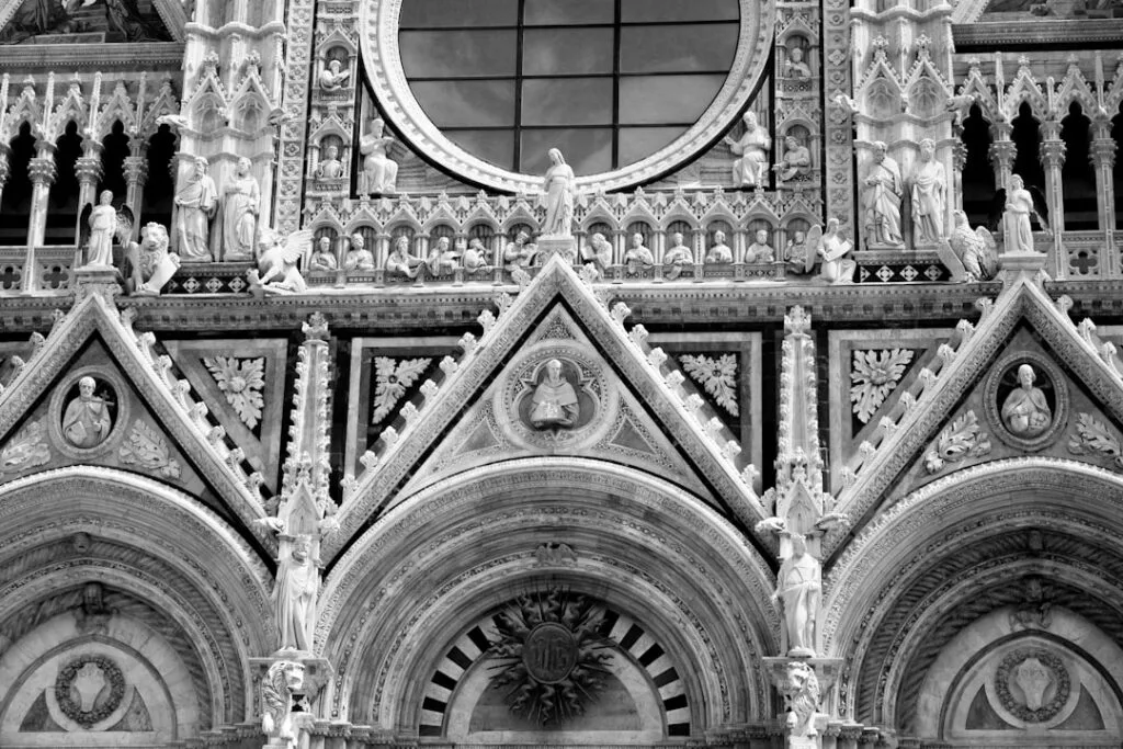 Nahaufnahme der detaillierten Fassadenstatuen und Rosette des Duomo von Siena