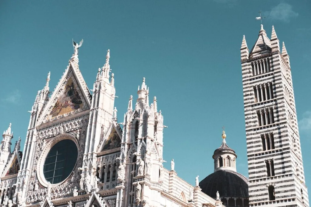 Façade sculptée et clocher rayé du Duomo de Sienne sous ciel bleu