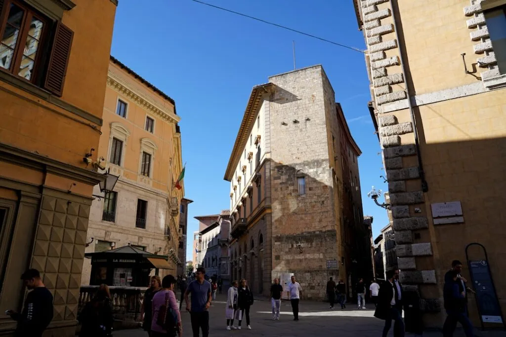 Rue animée de Sienne bordée de bâtiments historiques sous ciel bleu