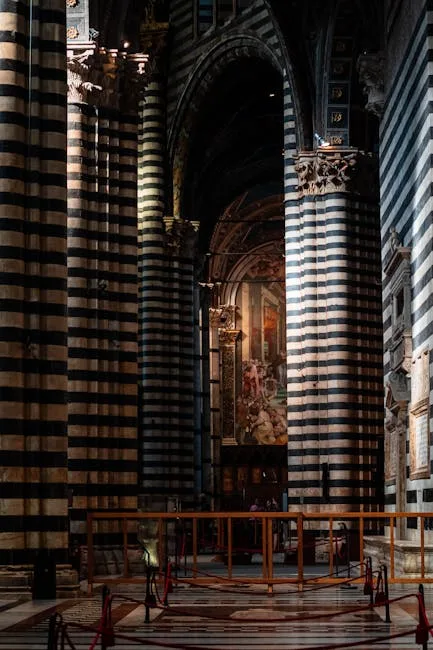Intérieur sombre du Duomo de Sienne, colonnes rayées noir et blanc