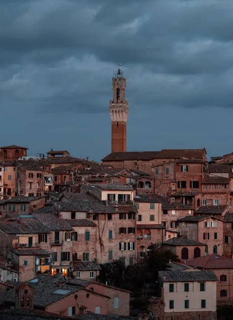 Toits de Sienne serrés autour de la Torre del Mangia sous ciel menaçant