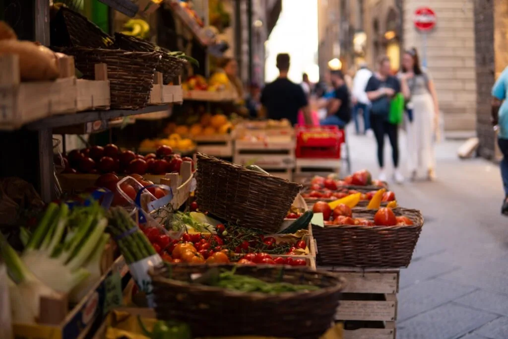 Straatmarkt met manden vol groenten en voorbijgangers in Siena