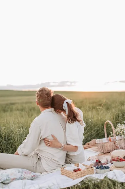 Couple enlacé sur une couverture, panier de pique-nique et champs