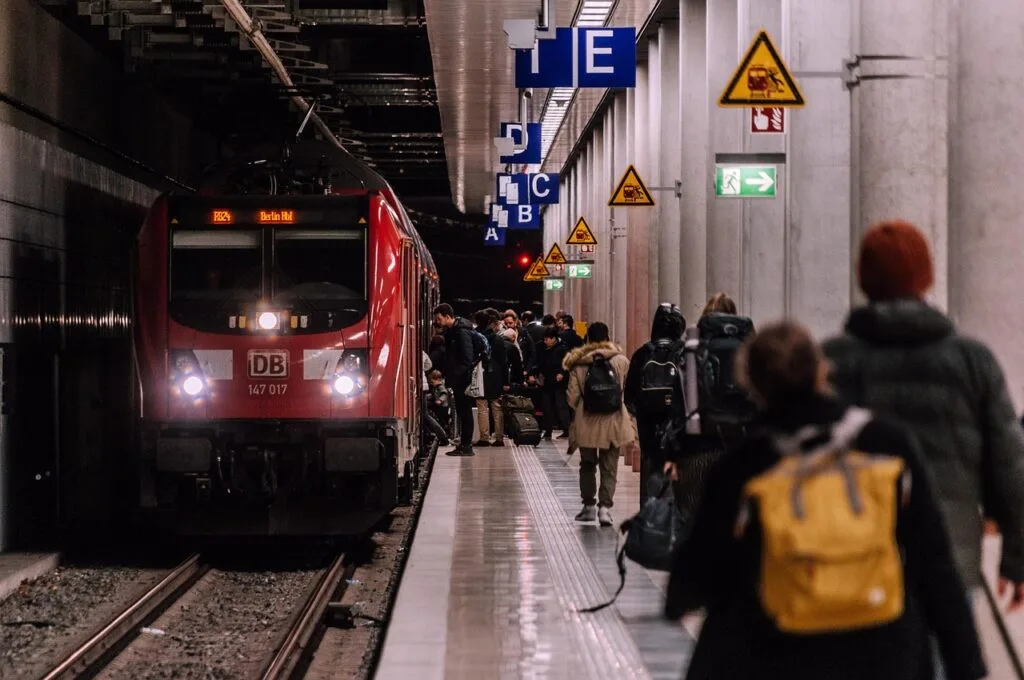 Voyageurs avec valises sur un quai de gare devant un train rouge
