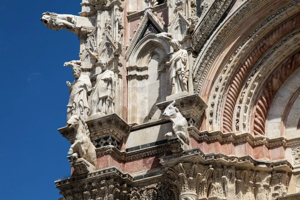 Détails sculptés et gargouilles en marbre rose sur le Duomo de Sienne