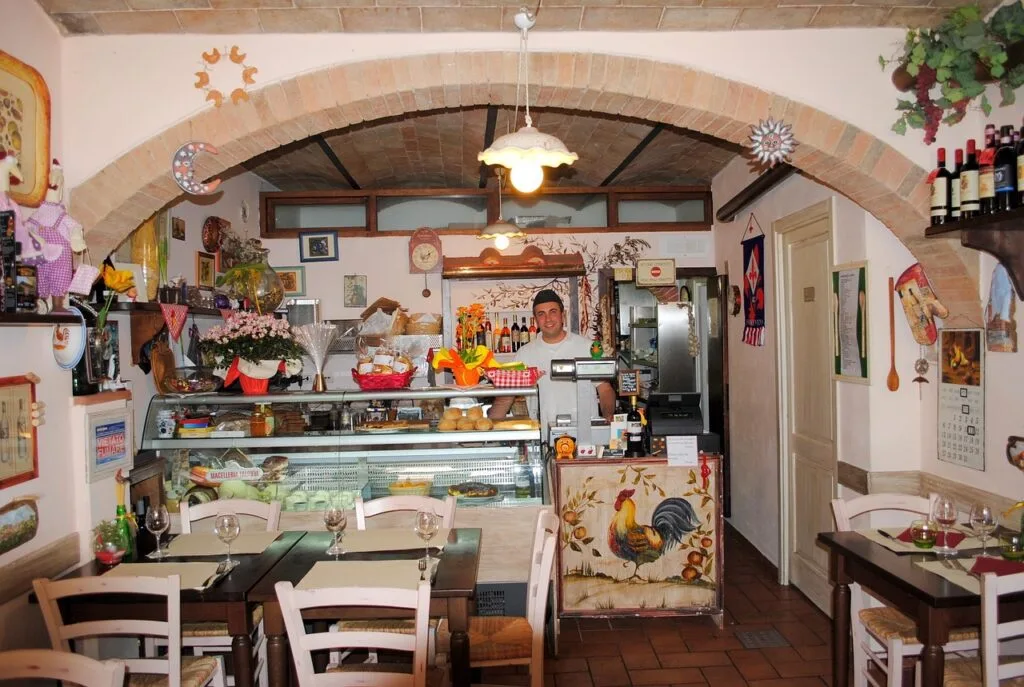 Intérieur d'une trattoria chaleureuse à Sienne avec patron souriant