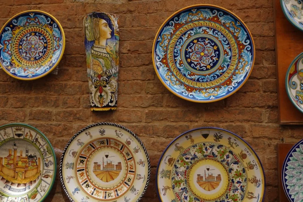 Assortiment d'assiettes céramiques décorées accrochées sur un mur à Sienne
