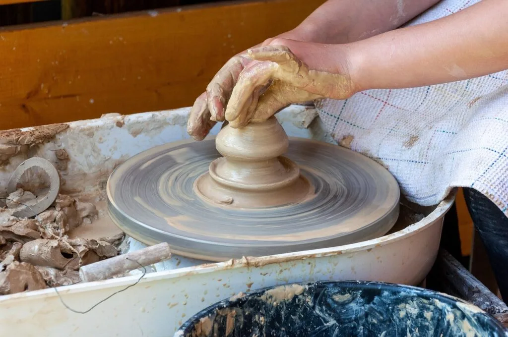 Mains en argile modelant un pot sur un tour de potier, atelier à Sienne