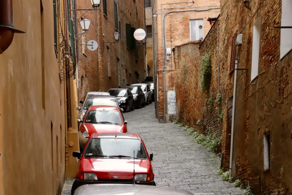 Ruelle étroite pavée de Sienne bordée de voitures garées